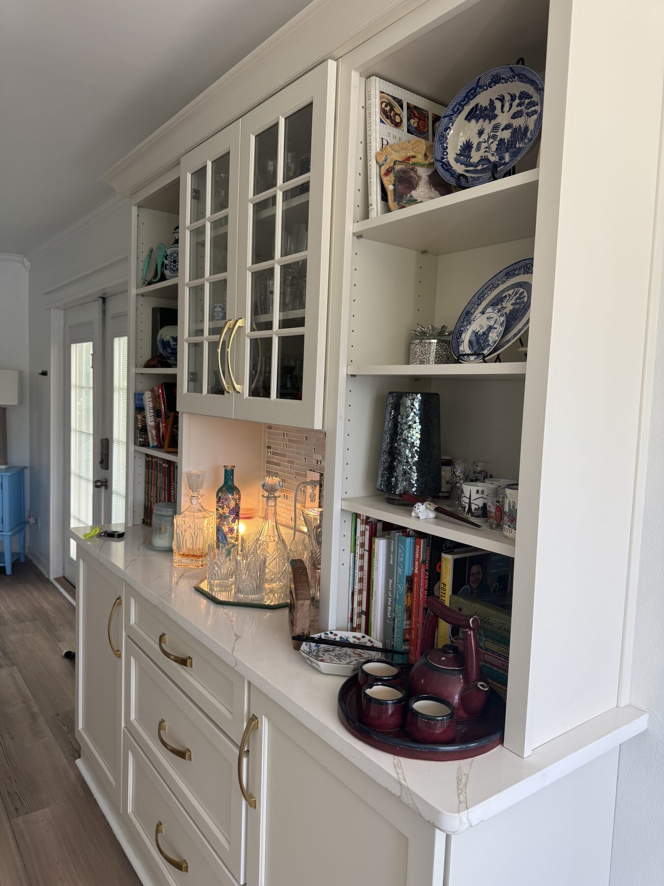 Built-in bar and bookshelf hutch with glass-front cabinets, cookbooks, and blue-and-white china