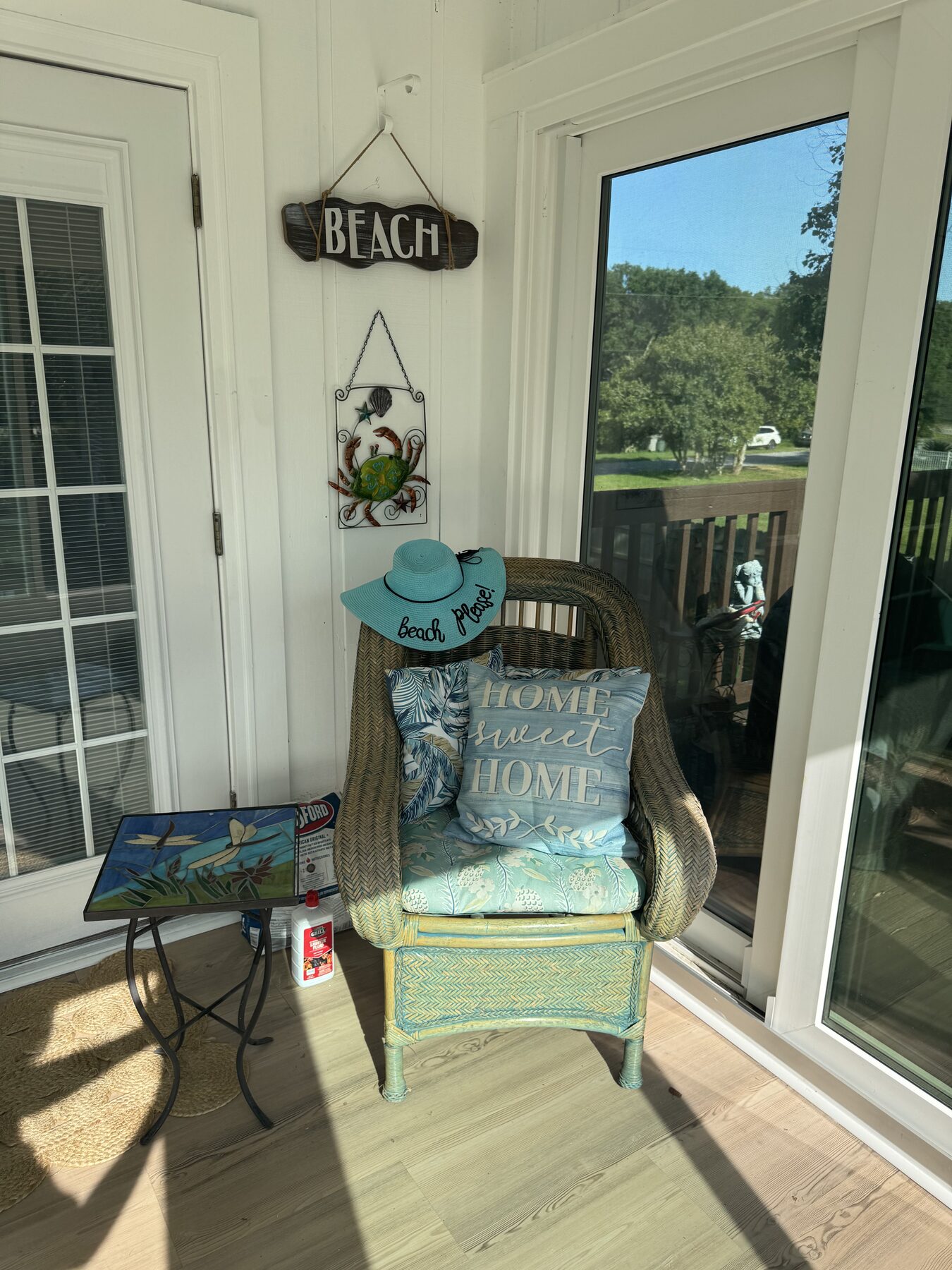 Cozy wicker reading chair with a Home Sweet Home pillow tucked into a sunny corner of the Florida room