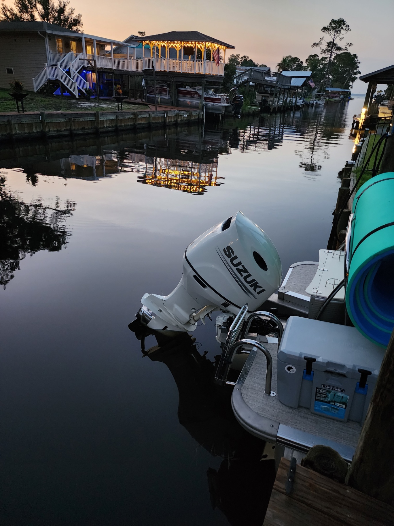 White Lotus at dusk, viewed from across the canal with boats at the dock