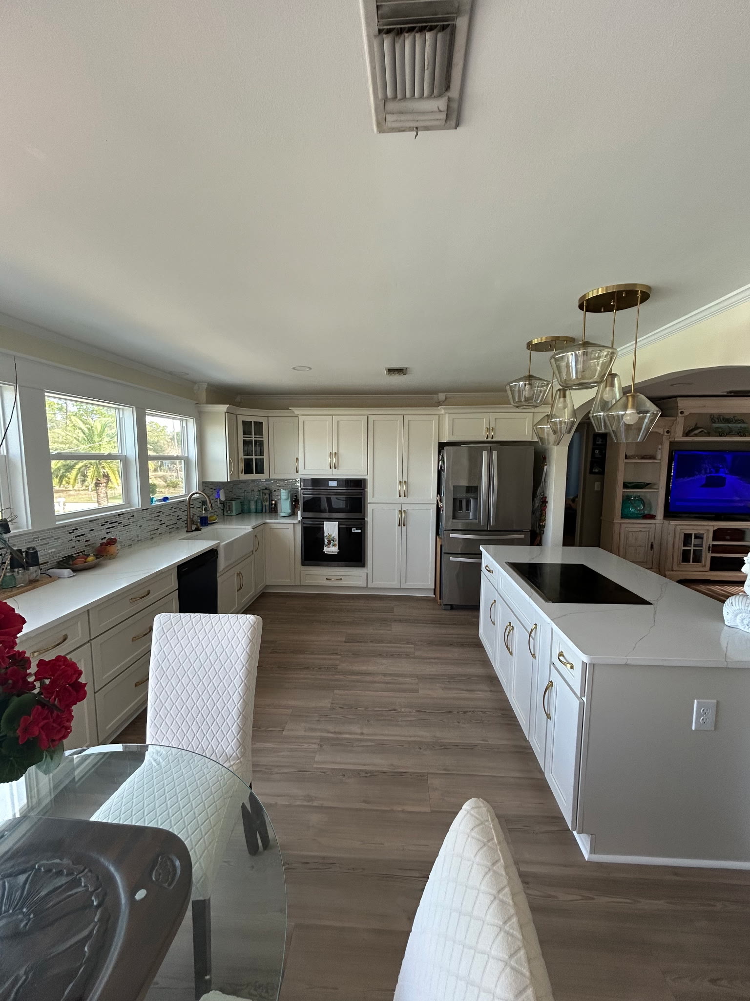 Fully equipped kitchen with white cabinetry, quartz counters, and brass pendant lights over the island