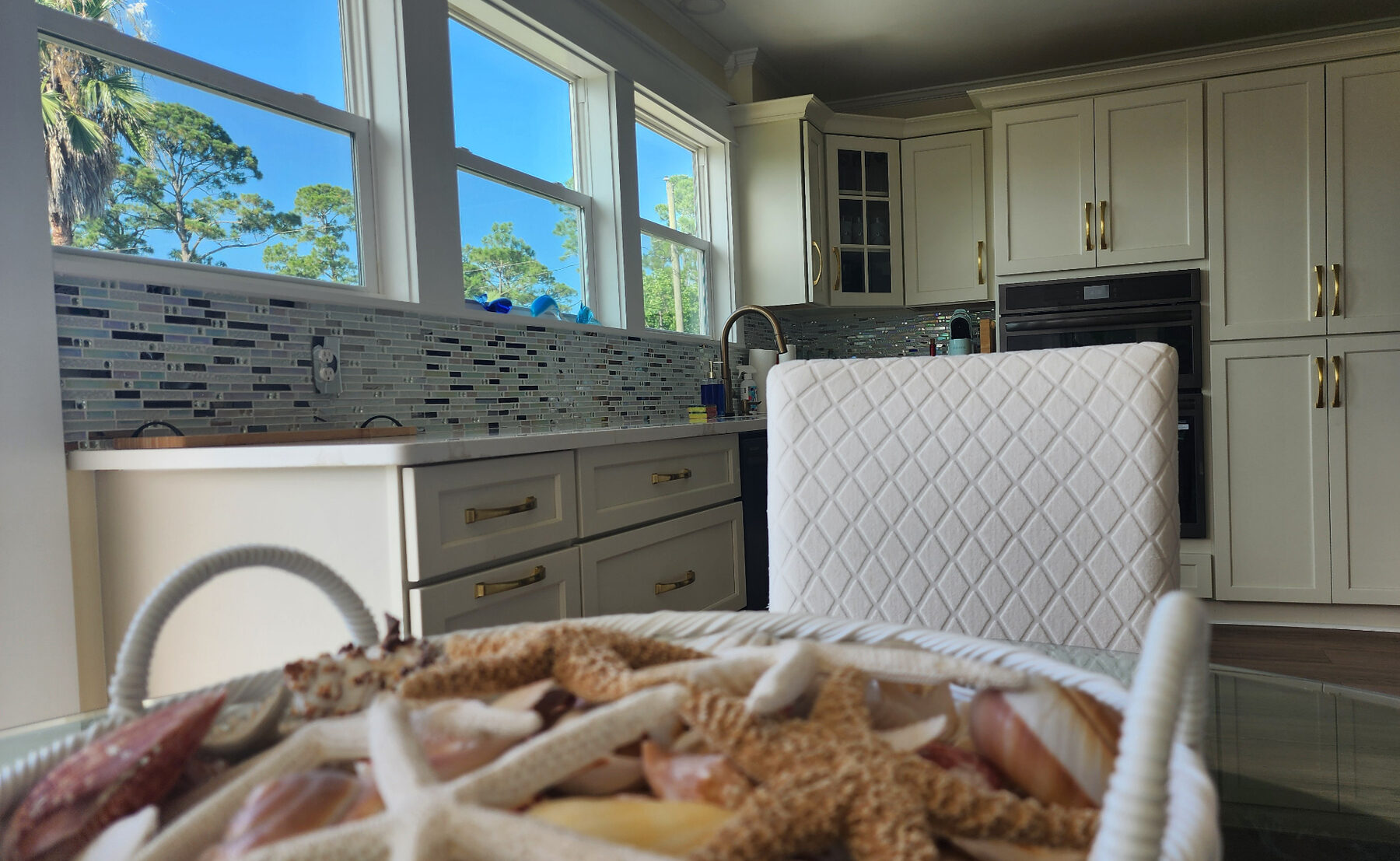 Kitchen counters with tile backsplash and a basket of seashells and starfish on the dining table