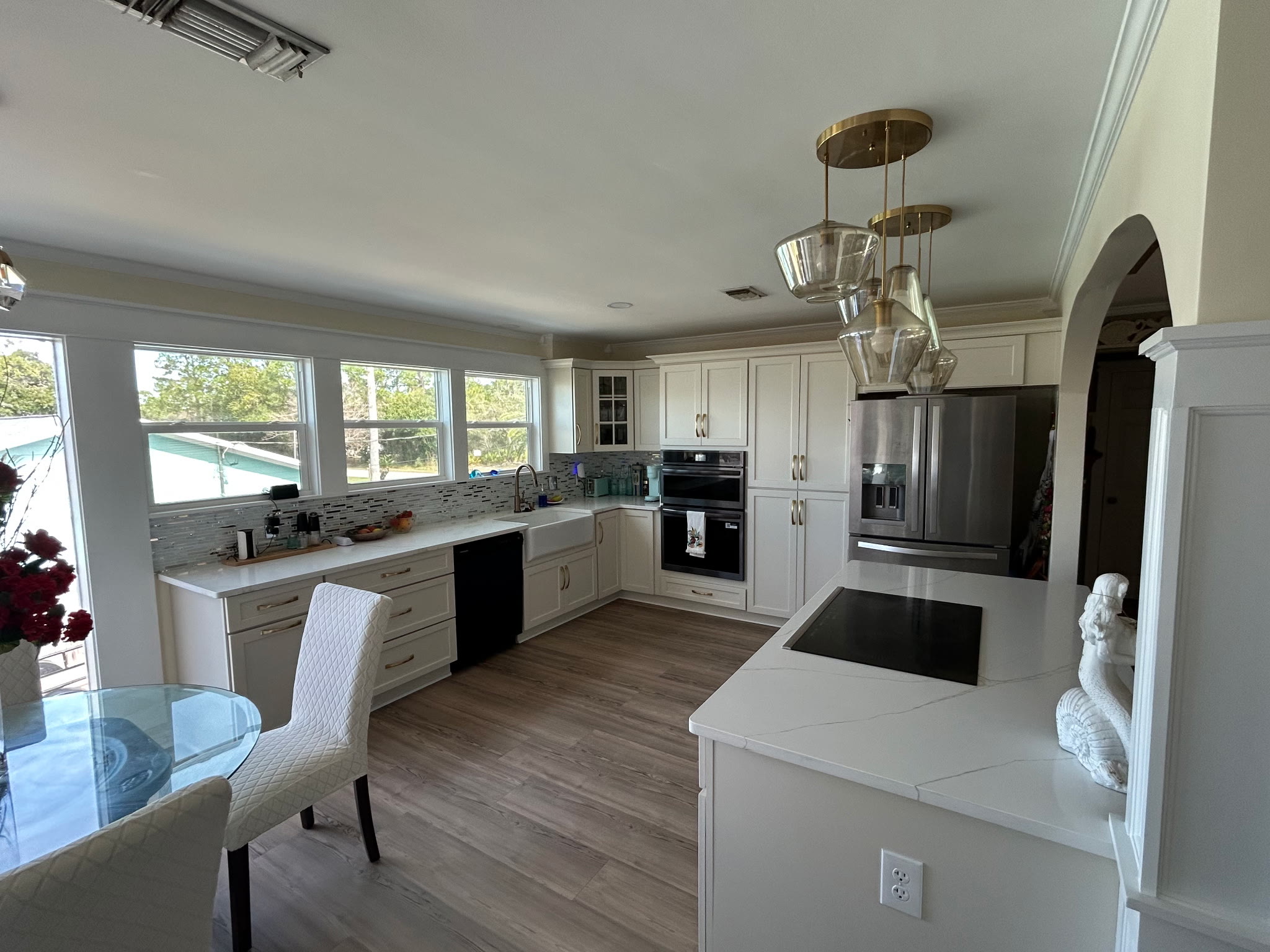 Kitchen from the dining side showing farmhouse sink, double ovens, and stainless refrigerator